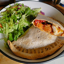 A wrap filled with halloumi and tomato served with salad