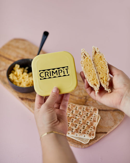 A person holding the CRIMPiT square and a toasted snack filled with macaroni cheese