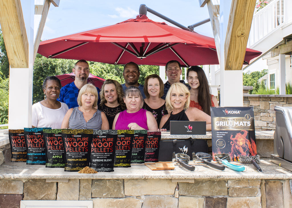 Kona team image with outside in outdoor kitchen with wood pellets displayed in front of us.