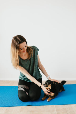 young lady playing with dashchund puupy on yoga mat