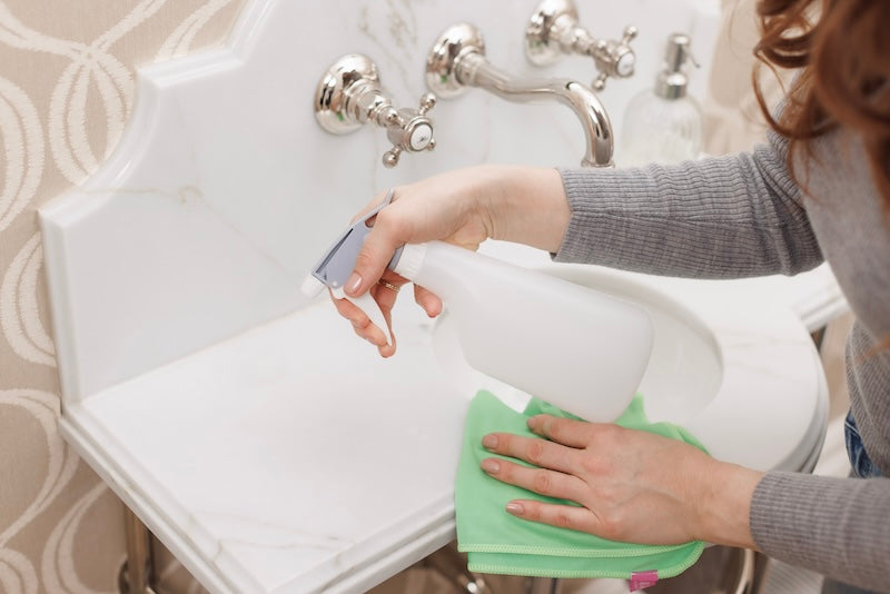 hand with spray bottle on sink