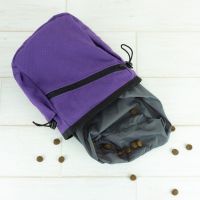 Purple canvas treat pouch laid flat with dog treats spilling out.