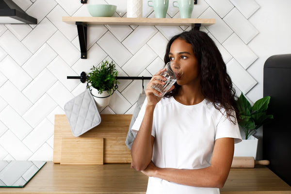 woman drinking glass of water in the kitchen
