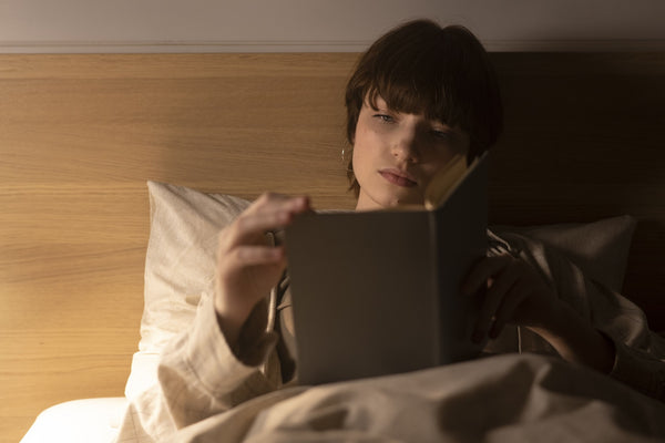 mujer descansando y leyendo un libro en la cama