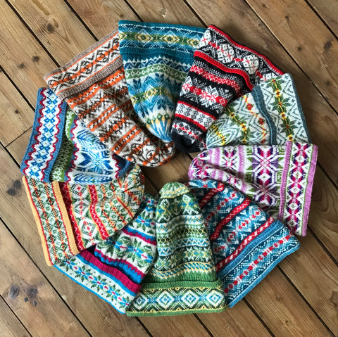 Ten colorful Fair Isle fisherman's keps or hats in a circle on a wood floor