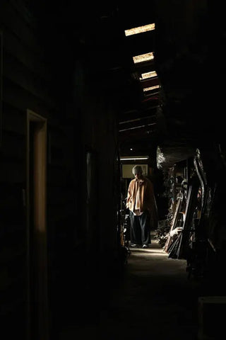 A man standing at the end of dark corridor filled with machine parts