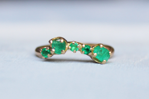 gold ring with several raw emerald stones