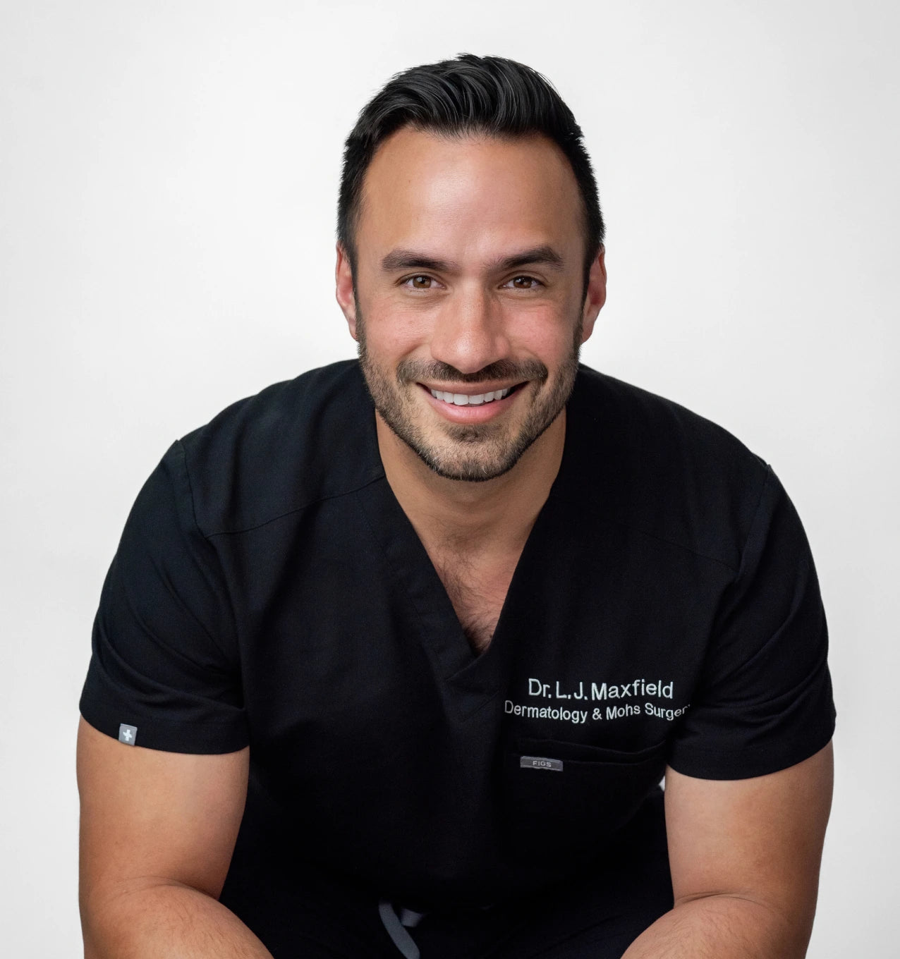 A person in a black medical uniform smiling at the camera.