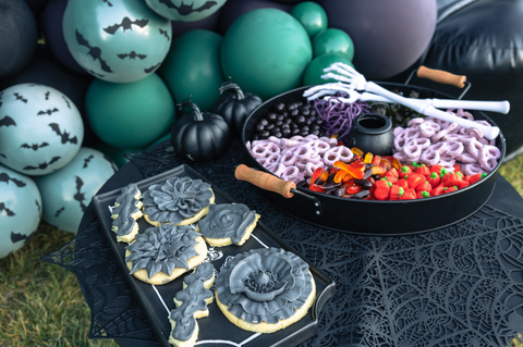 The candy buffet a little out of focus in the background with flower shaped cookies and grey frosting piped on