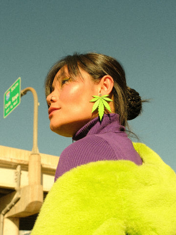 Wulan wearing neon green large leaf earrings in a purple and green outfit