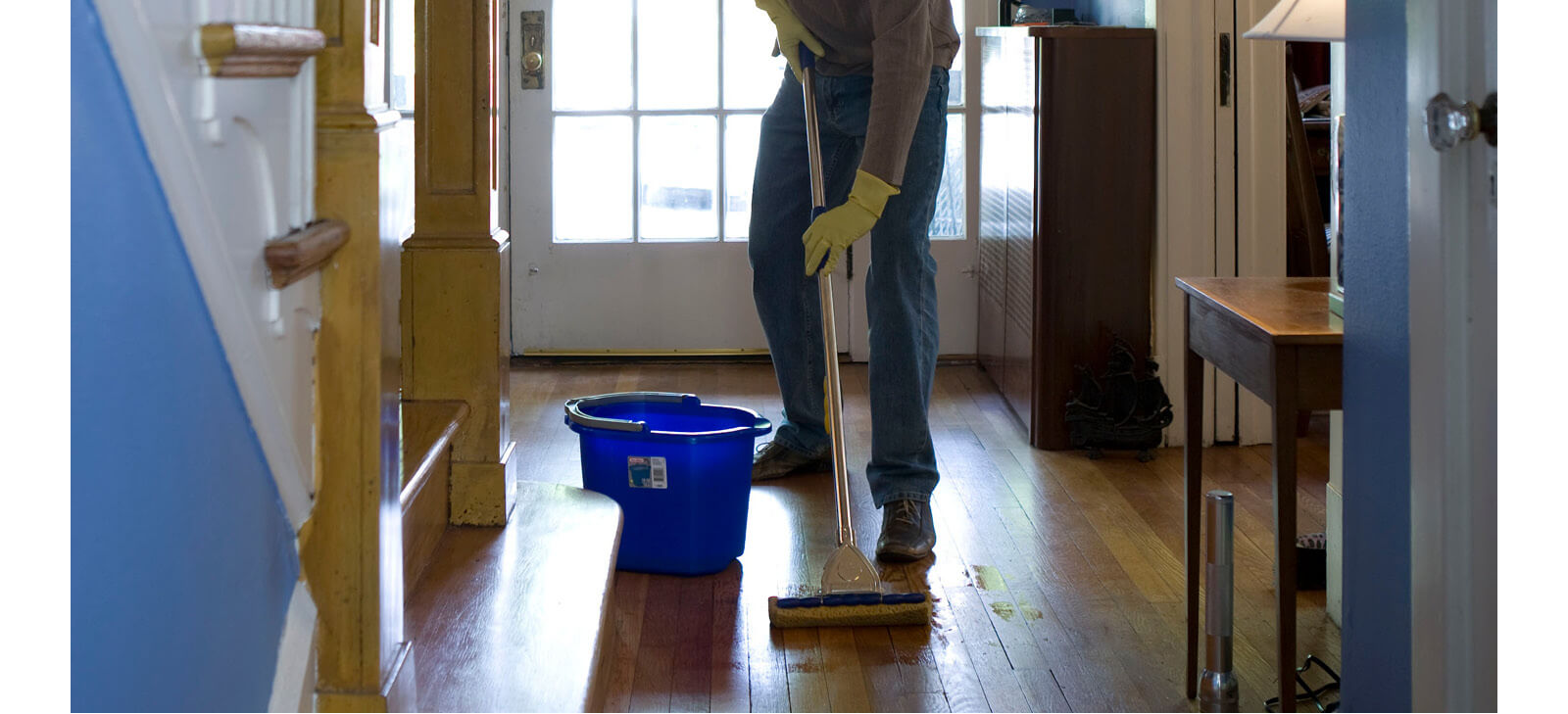 Man damp mopping an real wood entrance hallway