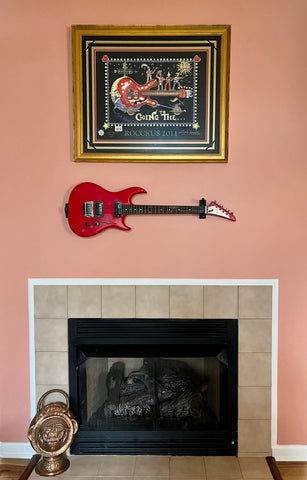 Horizontal electric guitar hanging on the wall under painting.