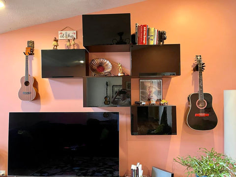 Tiki man guitar hanger and hand guitar hanger wall display next to flat screen tv.