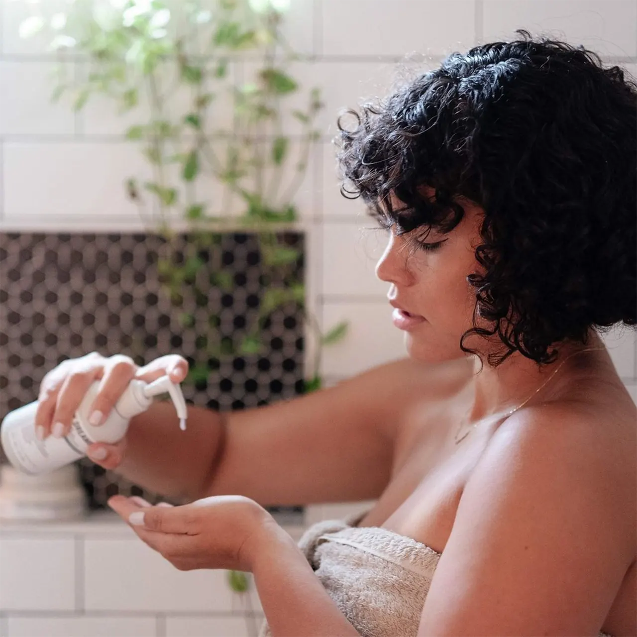 A woman is pouring shampoo into the palm of her hand.