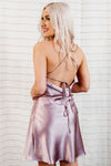Mauve-purple, silky satin slip mini dress with strappy back and flowy skirt on model.