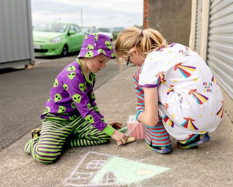 Hoopla Kids drawing on the concrete footpath outside the Stockroom, wearing colourful clothes from Moromini