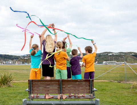 forexblackboxapp standing on a picnic seat, waving coloured streamers beside the Wellington airport runway