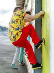 Child wearing PaperKrane Jungle shoes and bright clothing while climbing a green wall