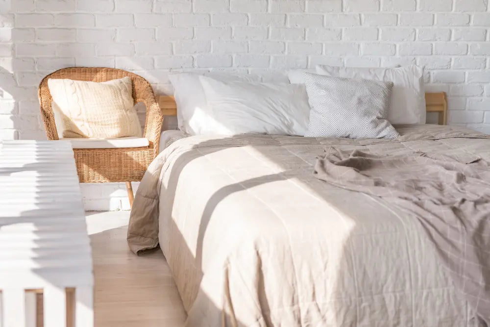 chambre à coucher avec matelas, mur blanc, lit blanc, fauteuil en osier 
