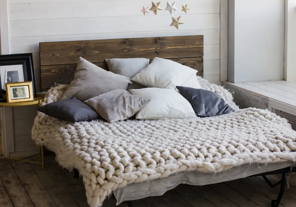 chambre à coucher avec lit et matelas, sommier en bois, mur blanc, couette en moumoute 