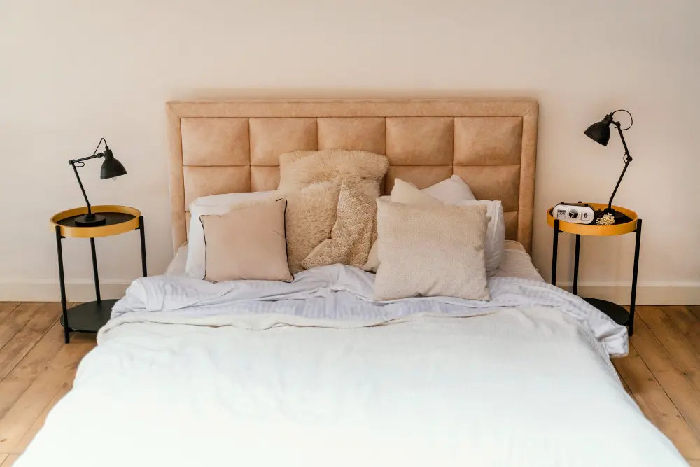 sommier beige avec lit blanc, parquet en bois, table de chevet avec lampe de chevet