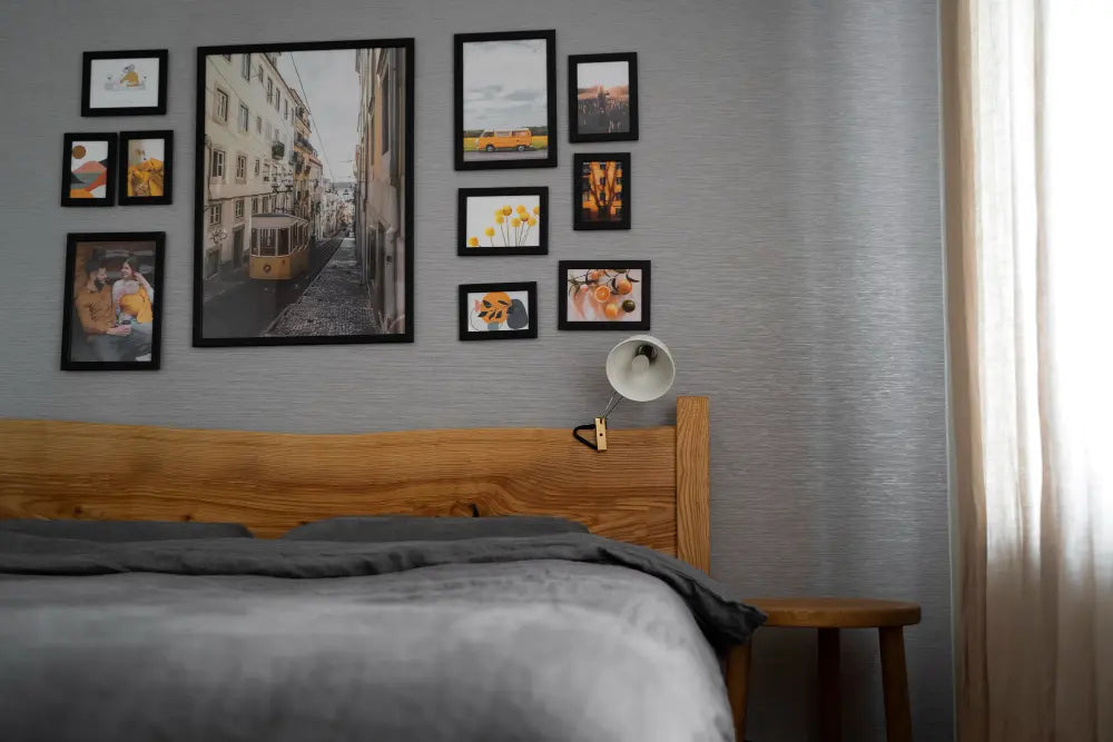 chambre noir et gris avec un mur gris, des cadres noirs, un sommier en bois, une lampe de chevet