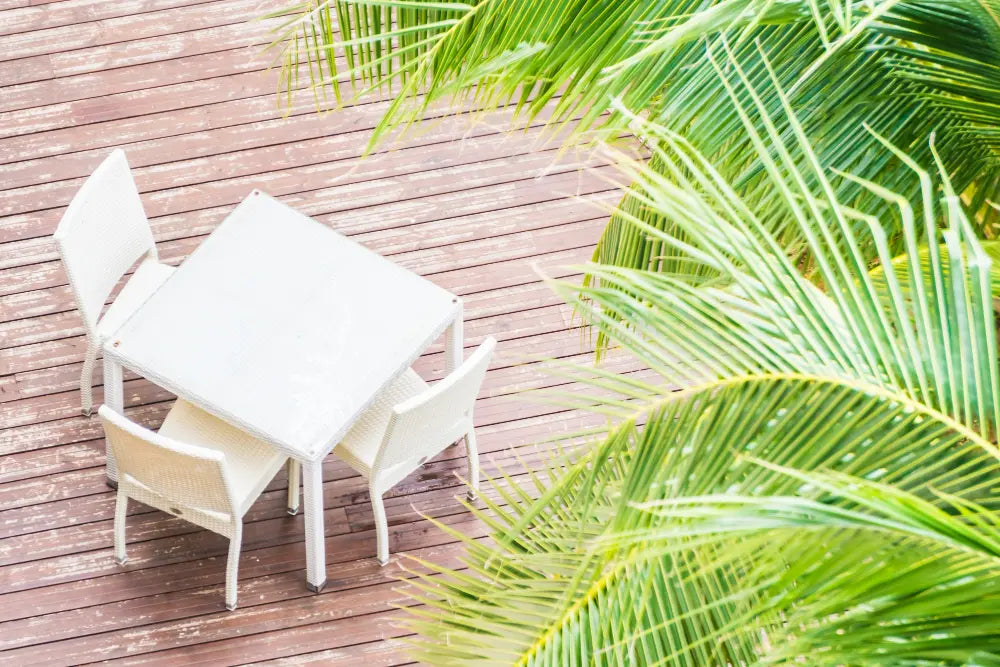 photo d'une terrasse en bois avec une table blanche bois et une plante verte 