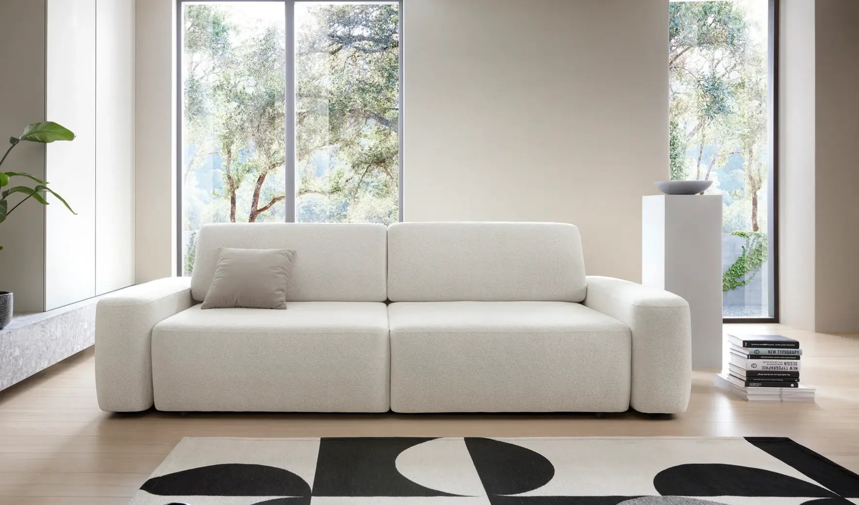 IVY - canapé 2 places blanc  dans un salon épuré avec une grande baie vitrée, un grand parquet en bois, un meuble tv, un tapis noir et blanc