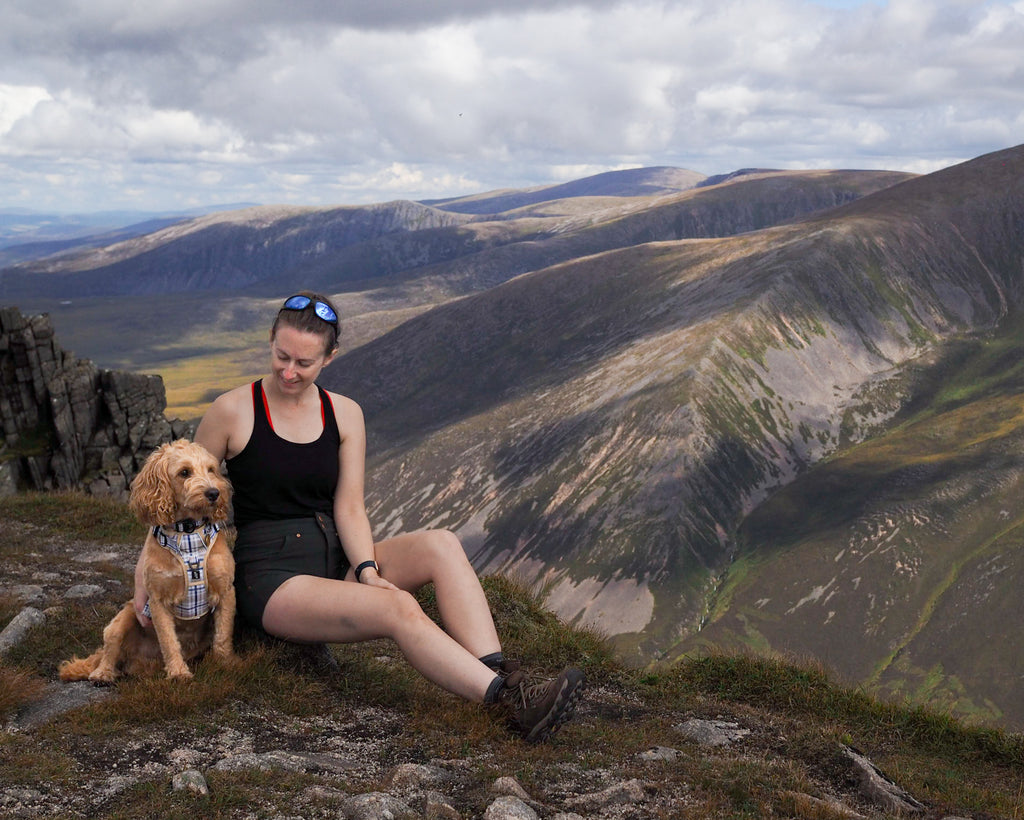 cockapoo and owner on scottish mountains with twiggy tags adventure harness and adventure collar in heritage
