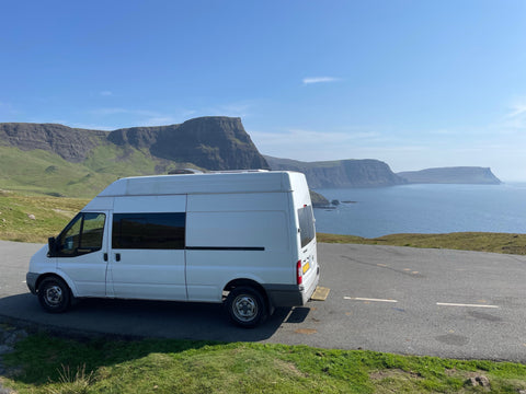 campervan parked up alongside the road in scotland, with mountain and sea scenery in the background