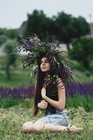 Girl with flower crown kneeling in a field