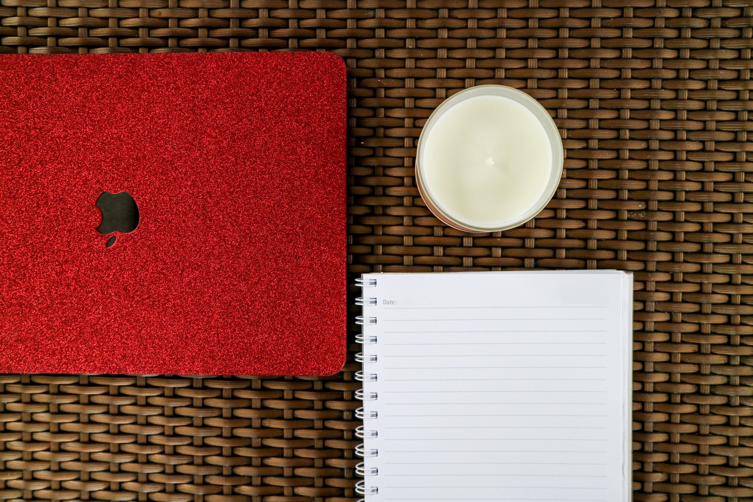 a macbook, notedbook, and a scented soy candle