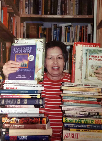 Author Donny Bailey Seagraves with books from the shelves of her home bookselling business, Junebug Books