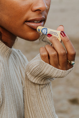 woman applying blue heron botanicals lip balm