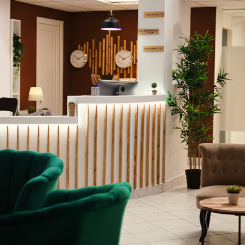 A hotel reception area with plants around the floor, desk and ceiling areas.