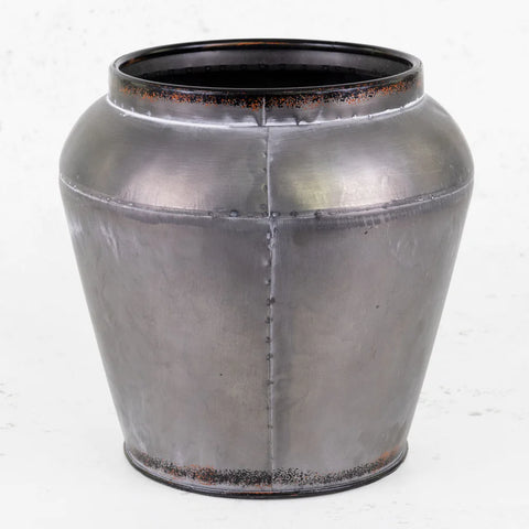 A large, dark grey, metal plant pot cover