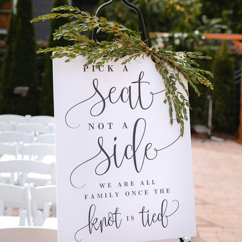 A welcome sign at a wedding decorated with sprigs of olive branches.