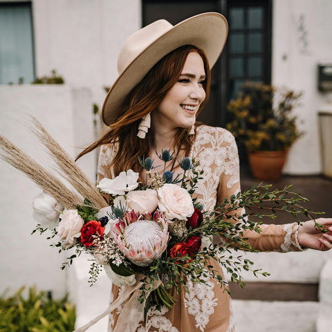 A young woman in a boho style wedding dress and boho bouquet