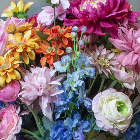 A group of boldly coloured artificial flowers close up.