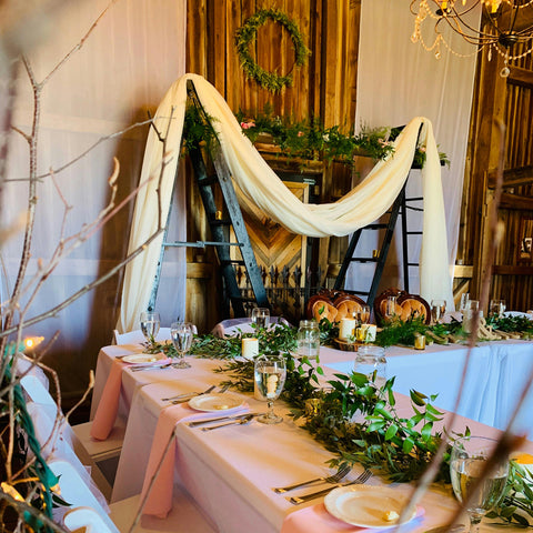 A rustic wedding reception venue, with flowers and foliage on the walls and table.