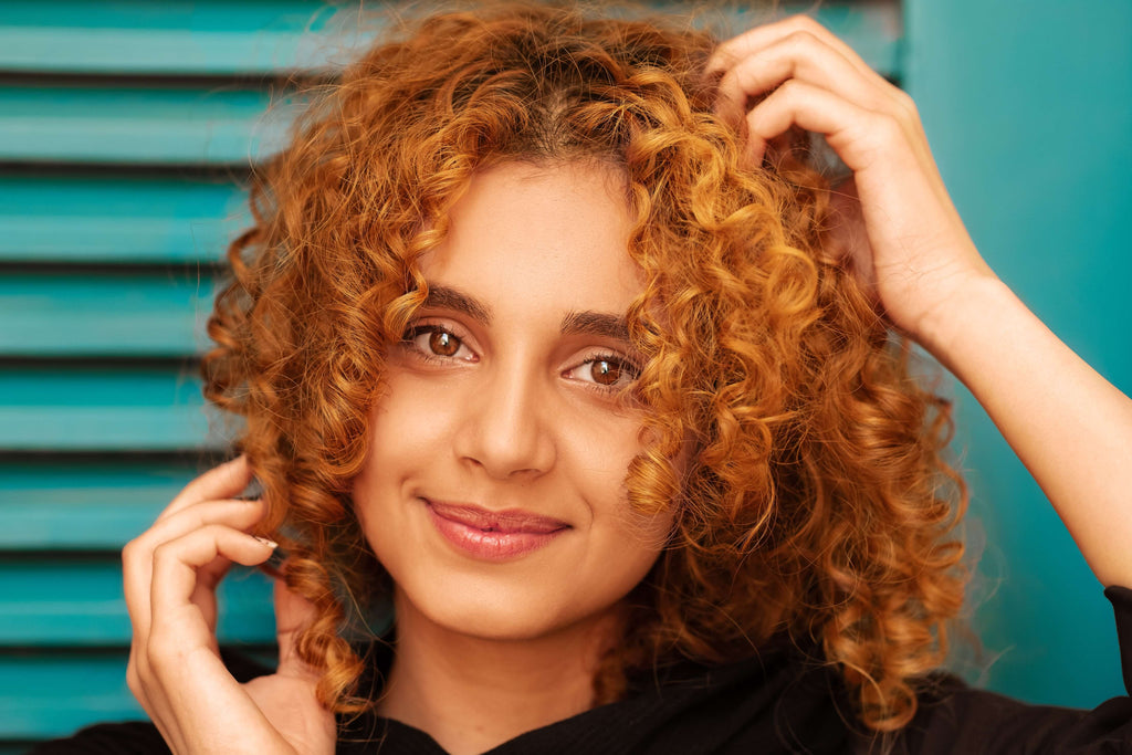 girl smiling at camera with hair touching curly hair