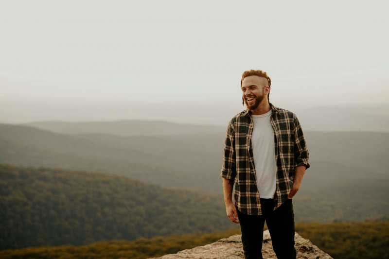 smiling man standing in front of mountains