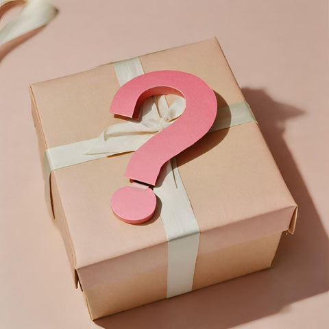 Ein rosafarbenes dreidimensionales Fragezeichen oben auf einer verpackten Geschenkbox