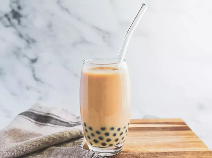 Brewed hojicha bubble milk tea in a glass with straw