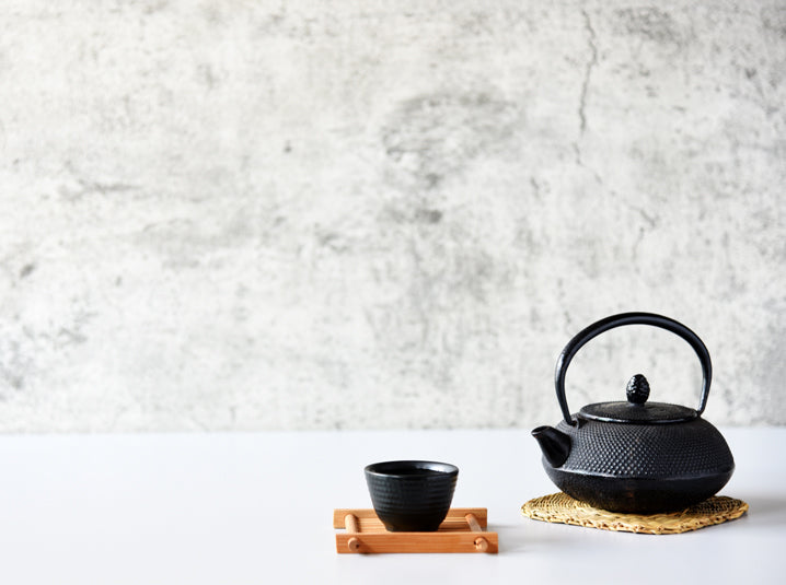 Black kyusu and yunomi on a white table with black and white stone background