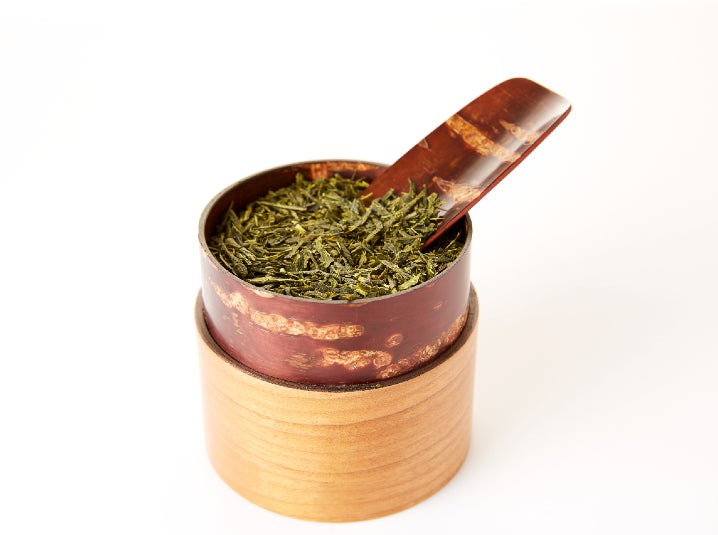 tea powder in a tea canister with cherry wood scoop
