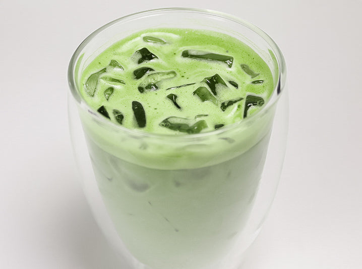 cold dairy-free oat milk matcha tea latte beverage in a double walled glass cup