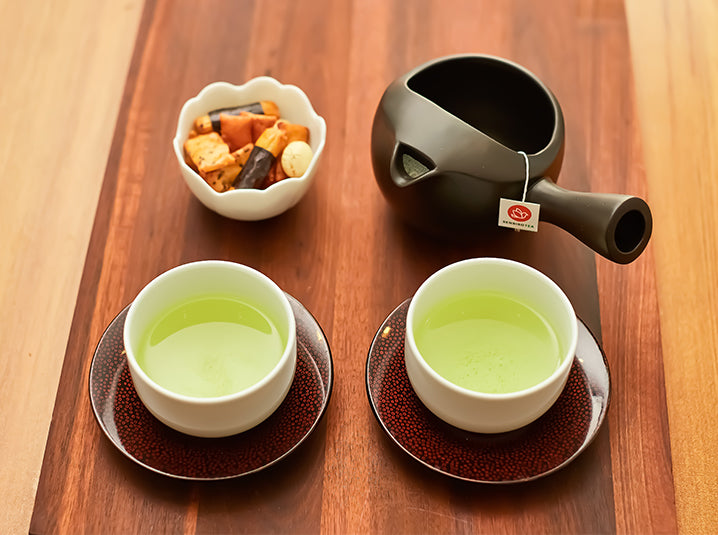 senbird organic sencha Japanese green tea two cups of being served on a red plate with black yokode kyusu teapot with senbird's tea pouch with Japanese