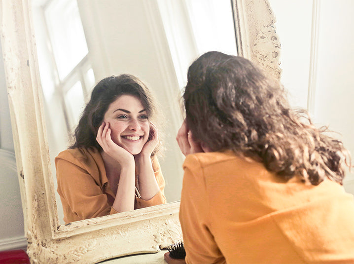 girl smiling in the mirror showing healthy teeth