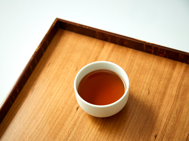 Brewed Hojicha Roasted Green Tea in a white cup on a dish